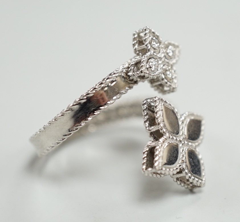 A modern stylish Italian 18kt white metal and four stone diamond set open flower head ring, maker RC with inset ruby?, size O, gross weight 5.2 grams.